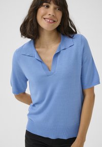 Light blue knitted pullover with a polo collar, short sleeves, and a ribbed hem. Features a relaxed fit and soft texture.