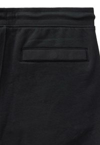 Close-up van zwarte stoffen shorts, met een elastische tailleband en een enkele horizontale achterzak met stiksels.