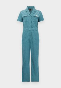 Teal kordfløyels jumpsuit med korte ermer, to brystlommer, en figursydd midje og rette ben, med et merke nær lommen.