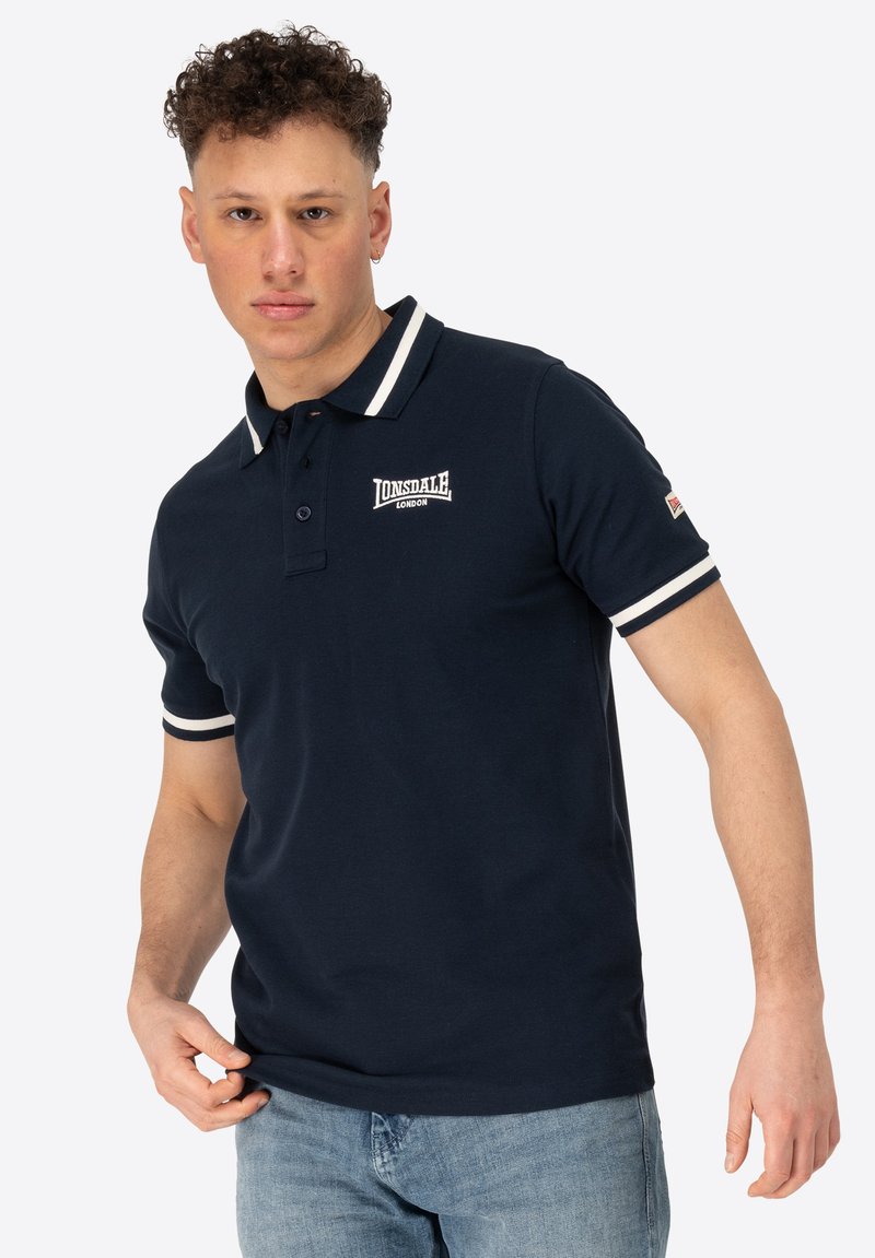 Marine polo t-shirt med hvidstribede krave og ærmeaccenter, med broderet logo på brystet, lavet af blødt bomuldsstof.