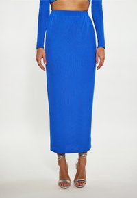 Lange blauwe geribbelde rok met een elastische tailleband, platte panelontwerp en een nette zoom. Gepaard met metallic zilveren bandjeshakken.