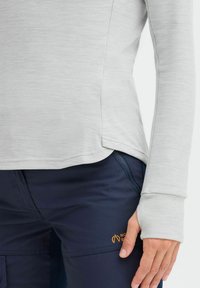 Lys grå langermet topp laget av myk stoff, med buet kant og tommelhull. Sammen med marineblå bukser med en oransje logo.