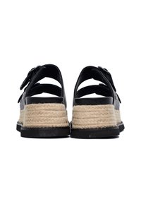 Sandali neri in pelle con una suola in juta intrecciata. Presentano cinturini alla caviglia, una superficie testurizzata e una suola in gomma nera.