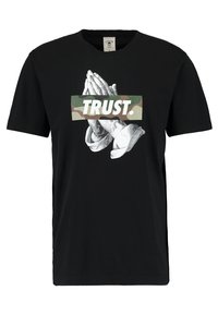 Sort bomulds T-shirt med et grafisk motiv af sammenfoldede hænder og ordet "TRUST." i camouflageprint. Korte ærmer og rund halsudskæring.