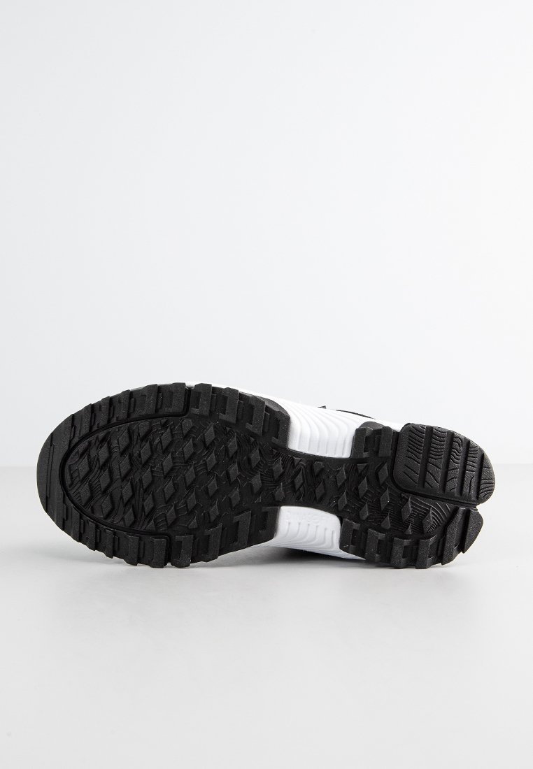 Semelle de sneaker en noir et blanc, face vers le haut, avec des motifs de semelle profonds sur une surface et un fond blancs.