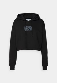 Crop hoodie nera realizzata in morbido tessuto. Presenta un logo grafico in blu e bianco sul davanti e cordini con punte metalliche.