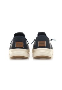 Zapatillas de tela en color marino con un perfil bajo, suela crema, detalles en cuero marrón y tiradores en la parte trasera para facilitar el calzado. Acabado texturizado en la parte superior.