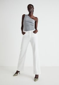 Asymmetrical grey bodysuit, white wide-leg jeans, and green pointed heels. Smooth fabric, fitted waist, high-rise cut, and flat front pockets.