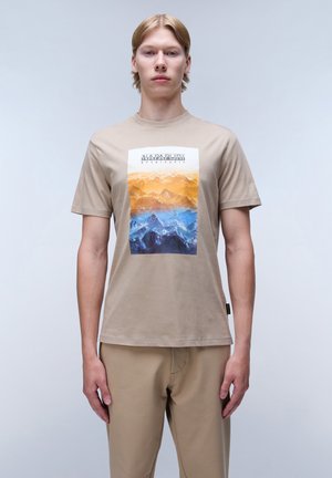 Camiseta de algodón de manga corta en color beige, con un gráfico colorido de montañas en naranja y azul, con cuello redondo y corte relajado.