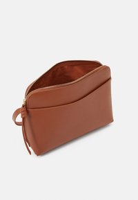 Ruskea nahkapussi, jossa on vetoketjukiinnitys, sileä pinta ja etutasku. Huomaamaton ompelu koristeena ja sivuhihna.