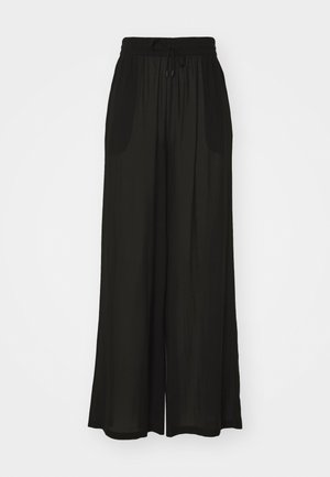 Pantalon large noir avec une taille élastique et un cordon de serrage, fabriqué dans un tissu lisse et léger, avec des poches latérales.
