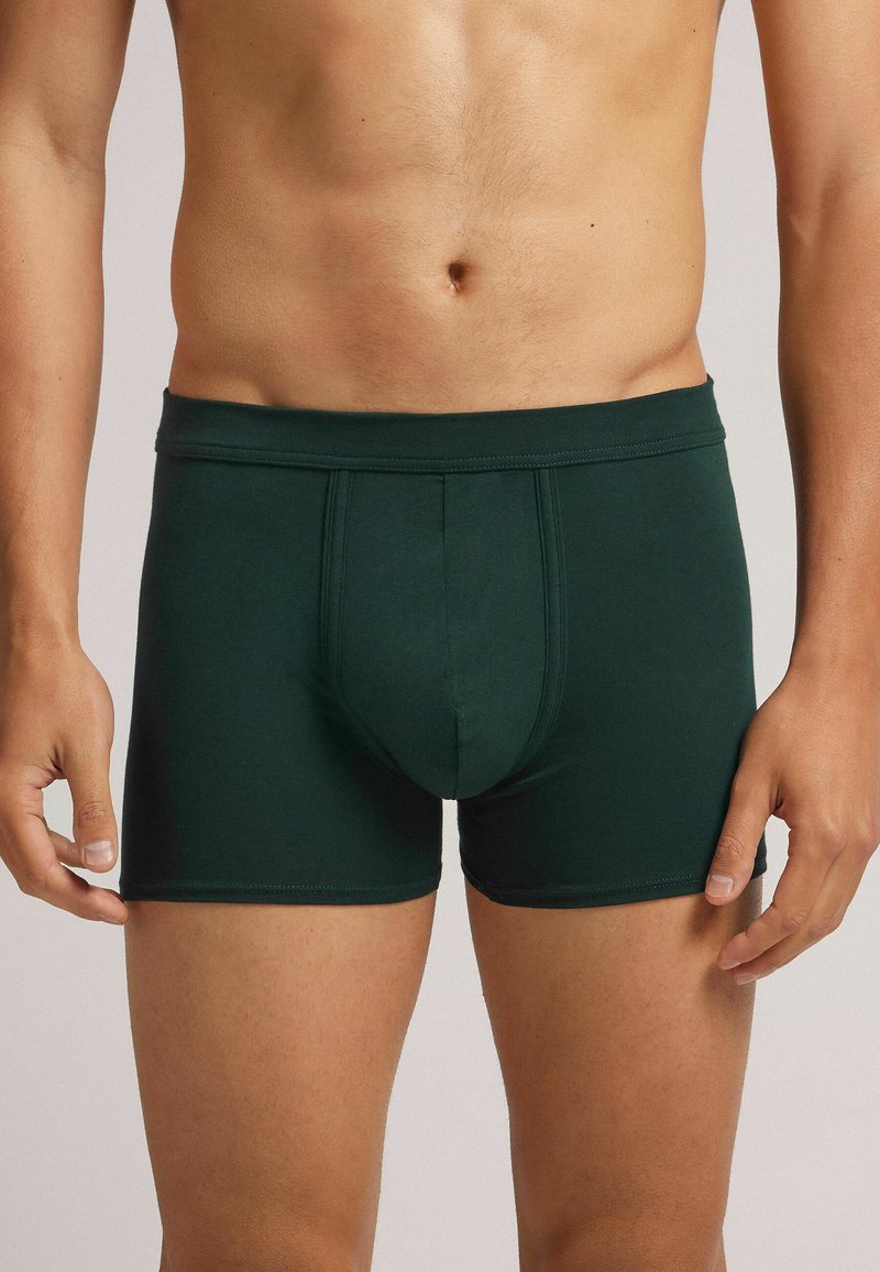 Tmavě zelené pánské boxerky vyrobené z hladké látky, s elastickým pasem a tvarovaným vakem pro podporu.