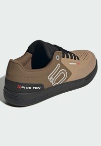 Ruskeat synteettiset pyöräilykengät mustilla aksentilla, rei'itetty muotoilu, kumipohja ja valkoiset logotiedot. Ominaisuuksiin kuuluu nauhakiinnitys.