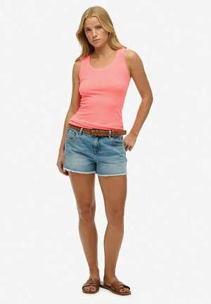 Débardeur sans manches rose vif, short en denim avec des bords effilochés, ceinture tissée marron et sandales marron à semelle plate.