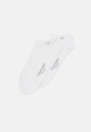 Meias brancas até ao tornozelo feitas de um tecido suave. Apresenta o logótipo "Calvin Klein" em cinza claro e marcas de tamanho na borda. Superfície lisa sem padrões.