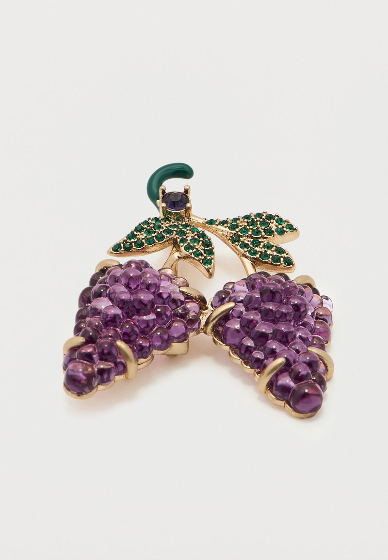 Goldbrosche in Form von zwei Trauben mit violetten Perlen und grünen, mit Juwelen besetzten Blättern auf weißem Hintergrund.