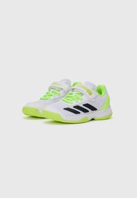 Scarpe da ginnastica bianche con strisce nere, dettagli in verde neon, tomaia in rete e suola testurizzata; presentano una cinghia in Velcro e lacci brillanti.