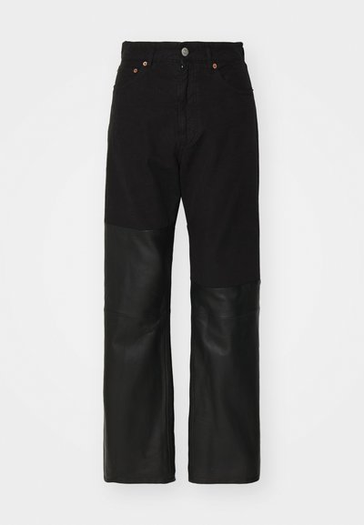 Black jeans with a wide-leg design featuring a contrasting leather panel from knee to hem. Cotton material with metal button and rivets.