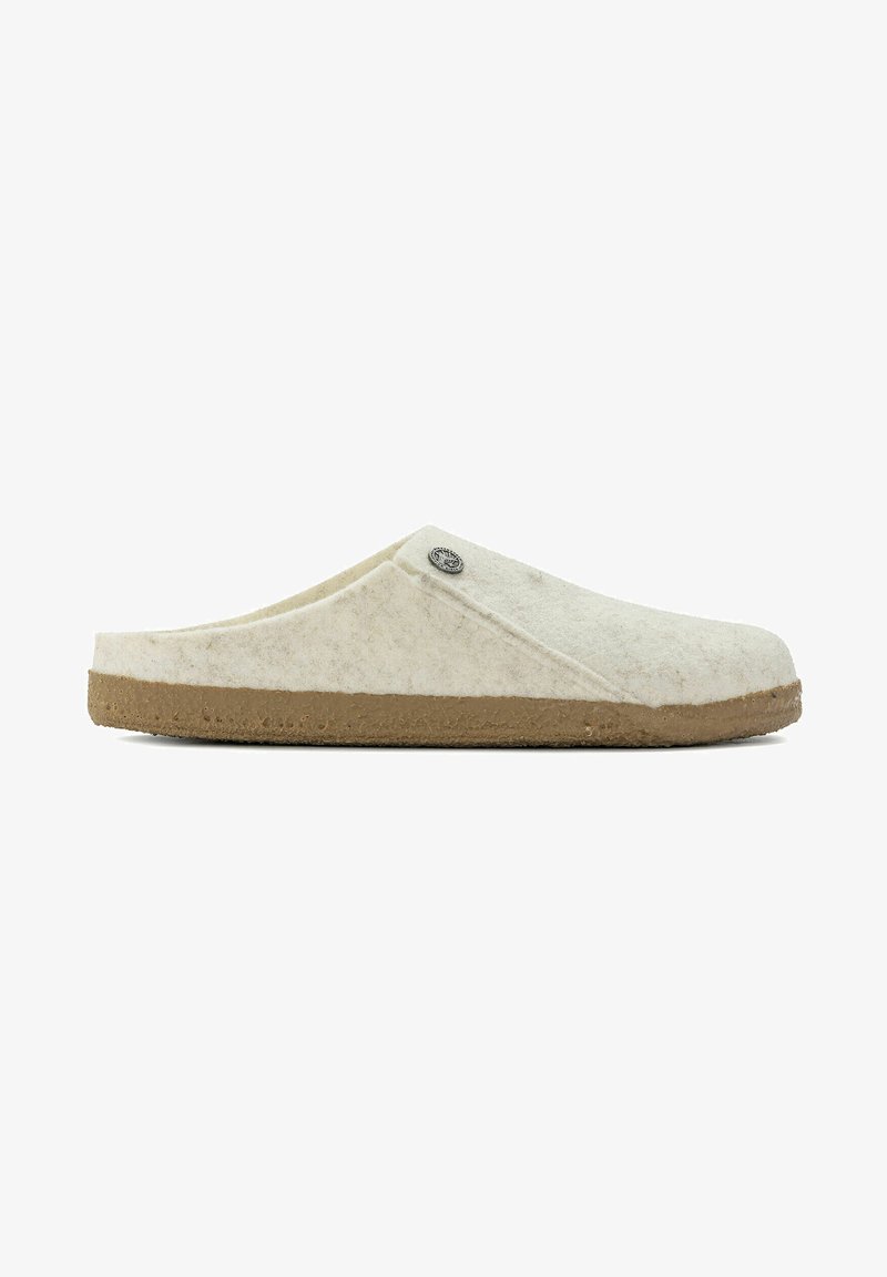 Wool slip-on slippers in light cream with a textured surface and a brown rubber sole; features a decorative metal logo accent.