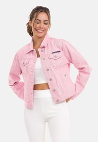 Lichtroze denimjack met een klassieke kraag, voortassen en zilveren hardware. Gekozen boven een witte ribbeltop en bijpassende broek.