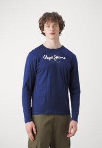 Tengerészkék, hosszú ujjú pamut póló, kerek nyakkal. Fehér "Pepe Jeans" logóval és alatta zöld "LONDON" felirattal rendelkezik.