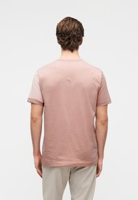 Κοντομάνικο T-shirt με στρογγυλή λαιμόκοψη σε ανοιχτό ροζ βαμβάκι, με λεία υφή και απλό, μινιμαλιστικό σχέδιο.