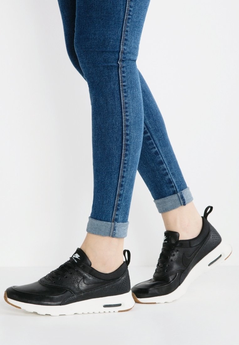 Svarta sportskor med en texturerad läderövre och vit gummisula. Funktioner inkluderar rundad tå, snörningsdesign och hälflik.