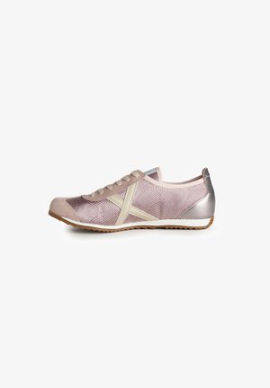Zapatilla deportiva de color rosa claro con tiras laterales en forma de X de color crema, puntera de ante, talón plateado metálico y suela de goma color beige, mostrada de perfil.