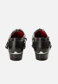 Schwarze Lederschuhe mit einem strukturierten Schlangenmuster, rotem Innenfutter und dekorativen Hardware-Akzenten. Leicht erhöhte schwarze Absätze.