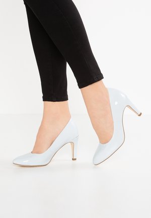 Lichtblauwe patenten leren hoge hakken met een spitse neus en een slanke hak. Draag ze met zwarte skinny jeans, wat een strakke afwerking laat zien.