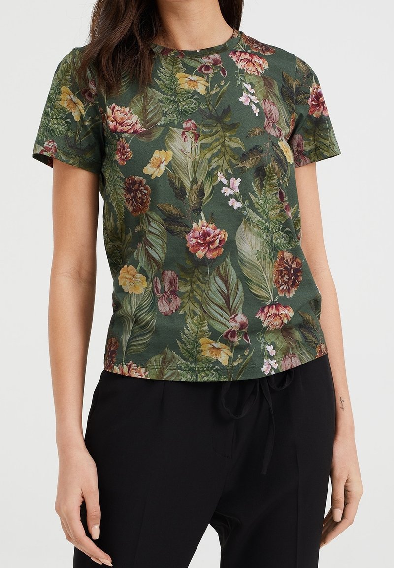 Tmavě zelené tričko s krátkým rukávem s květinovým potiskem, zobrazující různé květiny a listy. Měkká tkanina s volným střihem a kulatým výstřihem.