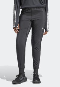 Zwarte trainingsbroek met een taps toelopend ontwerp, voorzien van zijpaneelstiksels, een elastische tailleband en het Adidas-logo op de linkerdij.