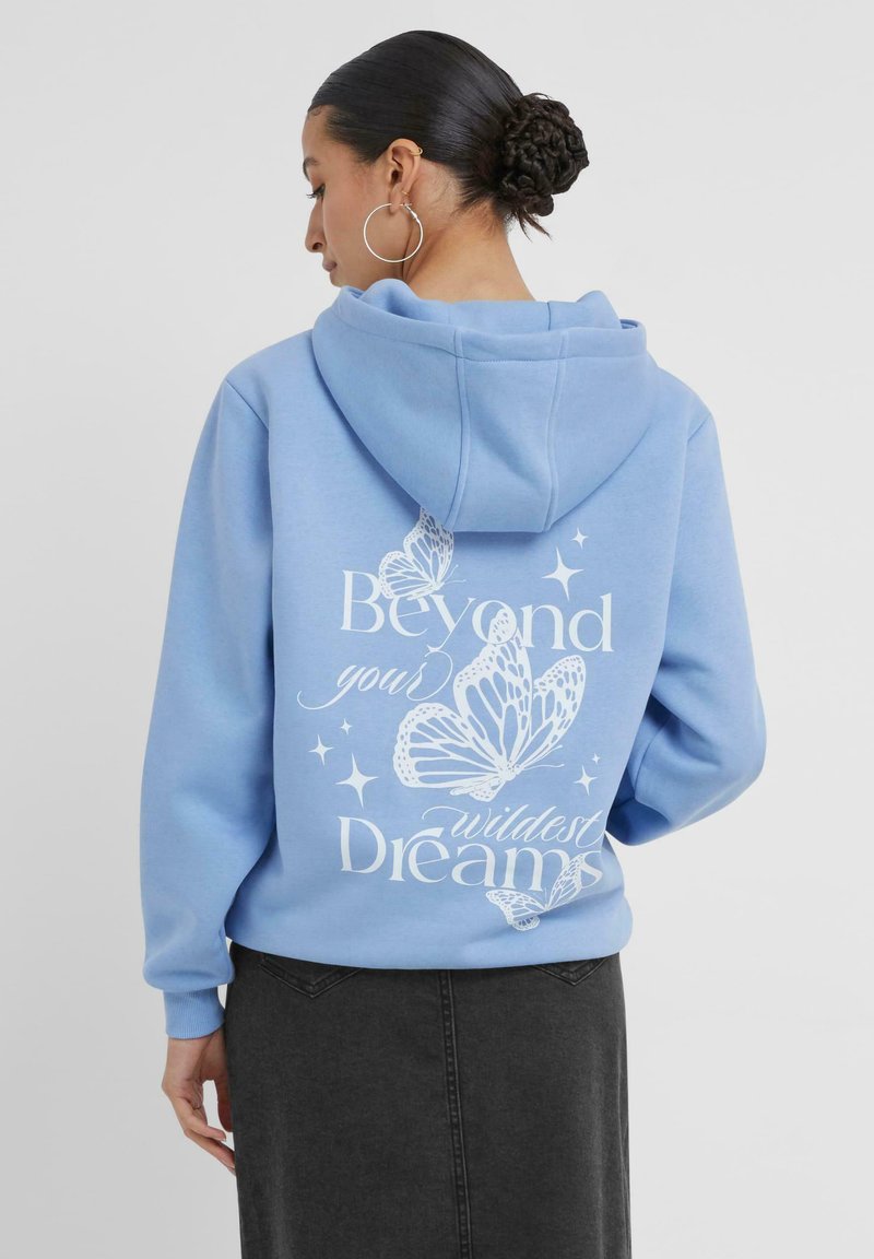 Felpa con cappuccio azzurro chiaro, decorata con testo grafico bianco e disegni di farfalle sul retro. Presenta una vestibilità rilassata e polsini a coste.