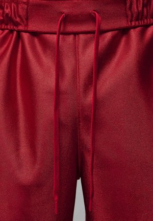 Shorts de sport rouges en tissu texturé et côtelé, avec une taille élastique et un cordon de serrage pour un ajustement personnalisable.