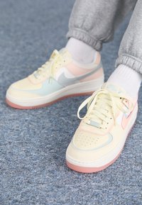 Pastellfärgade sneakers med läderexteriör, med ljusgula, blåa och rosa accenter. Gummisula med strukturerad ljusrosa botten.