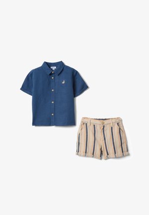 Camisa azul marino de manga corta con botones y logo de velero, combinada con pantalones cortos a rayas verticales en beige, azul y naranja con cierre de botones.