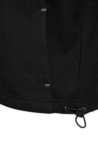 Nahaufnahme eines schwarzen Stoffes mit zwei kleinen grauen ovalen Knöpfen und einem verstellbaren elastischen Kordelzug mit einem schwarzen Stopper am Saum.