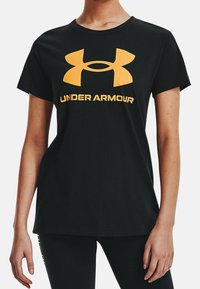 Zwart katoenen T-shirt met een groot geel Under Armour-logo op de borst. Korte mouwen en een klassiek ronde halsontwerp.