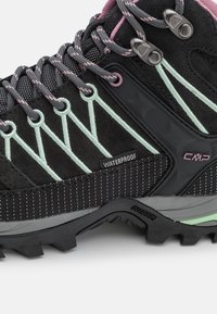Botas de senderismo negras con acentos en gris y menta, material impermeable, ante texturizado y suela de goma robusta. Presenta ojales metálicos y cordones.