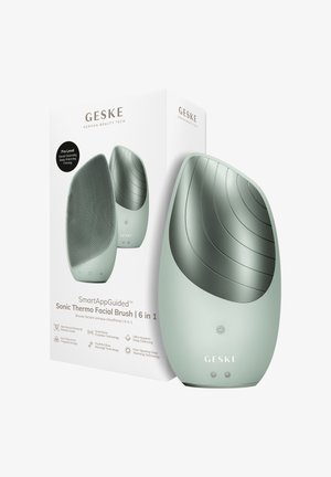 Strakke, muntgroene 6-in-1 sonische thermo gezichtsborstel met getextureerde voorkant, gladde achterkant en twee bedieningsknoppen naast de productverpakking.