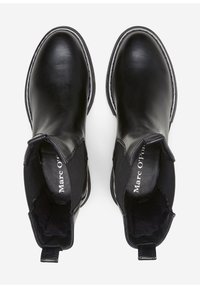 Ein Paar schwarze Leder-Chelsea-Boots zum Hineinschlüpfen mit Zugschlaufen, elastischen Seitenteilen und markierten Innensohlen auf einem weißen Hintergrund.