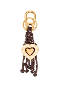 Gold heart-shaped charm with cutout center and engraved letters, attached to brown braided cord and loop, featuring tassel ends and beads.