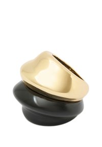 Bague imposante en or et noir avec une surface lisse et polie, au design arrondi et aux formes superposées, mettant en valeur des finitions contrastées.