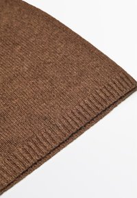 Bruine gebreide beanie met geribbelde zoom. Zachte textuur en gelijkmatige steekpatroon, taps toelopend ontwerp voor een nauwsluitende pasvorm.