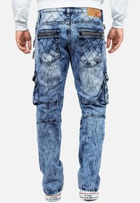 Pantaloni cargo in denim con un lavaggio azzurro chiaro sbiadito, tasche posteriori imbottite, dettagli in metallo sulla cerniera e una vestibilità comoda.