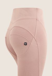 Pantaloni elasticizzati rosa con una texture liscia, vestibilità su misura e dettagli di cucitura curva. Presentano un piccolo logo del marchio nero sulla tasca posteriore.