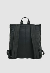 Zaino in pelle nera dalla forma piatta, con due spallacci imbottiti, una maniglia superiore e una texture liscia. Nessun motivo o dettaglio metallico visibile.