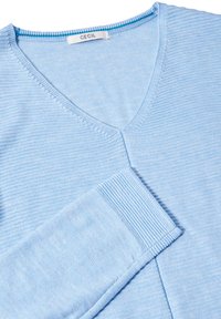 Ljusblå V-ringad tröja i texturerad stickad tyg. Har ribbade ärmslut och fåll med subtil randig mönster. Etikett: CECIL.