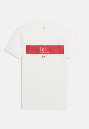 Camiseta blanca de manga corta de Nike con un panel rectangular rojo que presenta la bandera de Turquía y un swoosh rojo de Nike debajo.