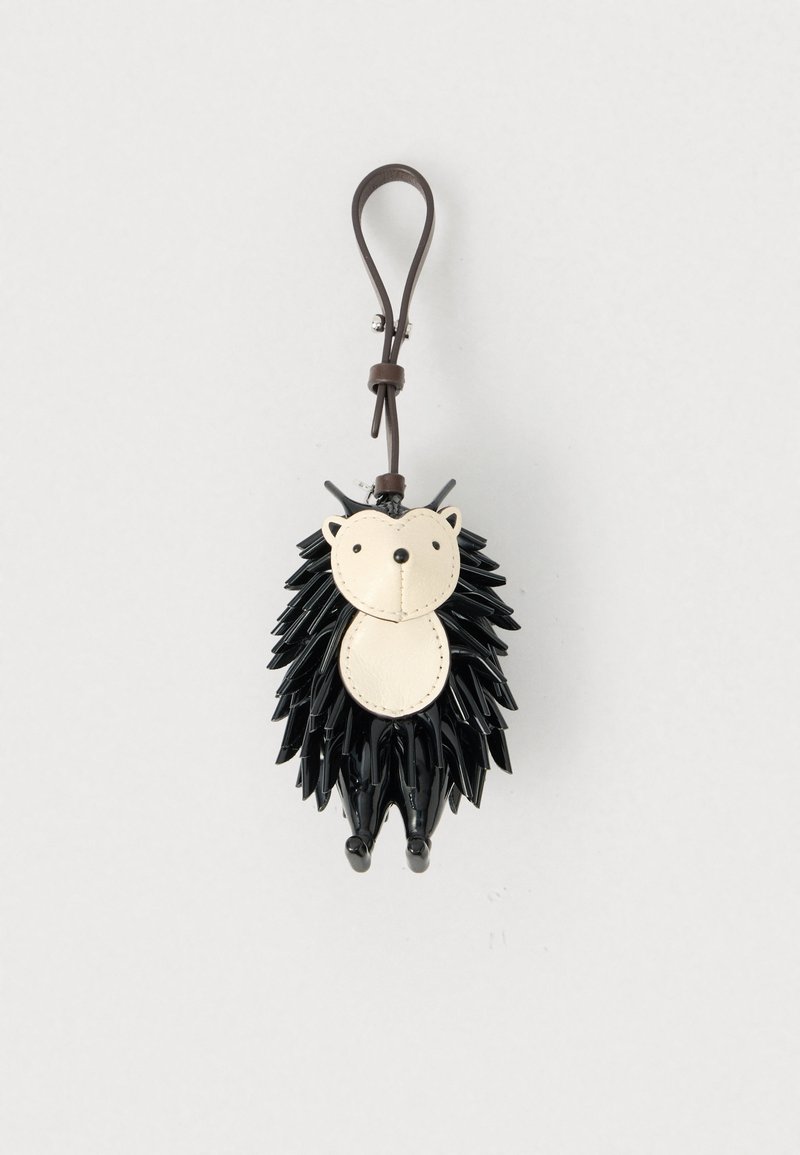 Breloc cu arici negru realizat din materiale texturate; are fața de culoare crem, urechi ascuțite și picioare mici, cu o curea maro.